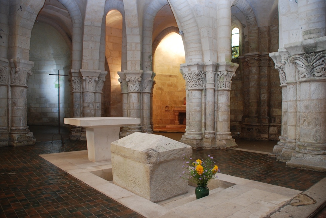 En medeltida stensarkofag i en vacker romansk krypta med utsmyckade pelare.
